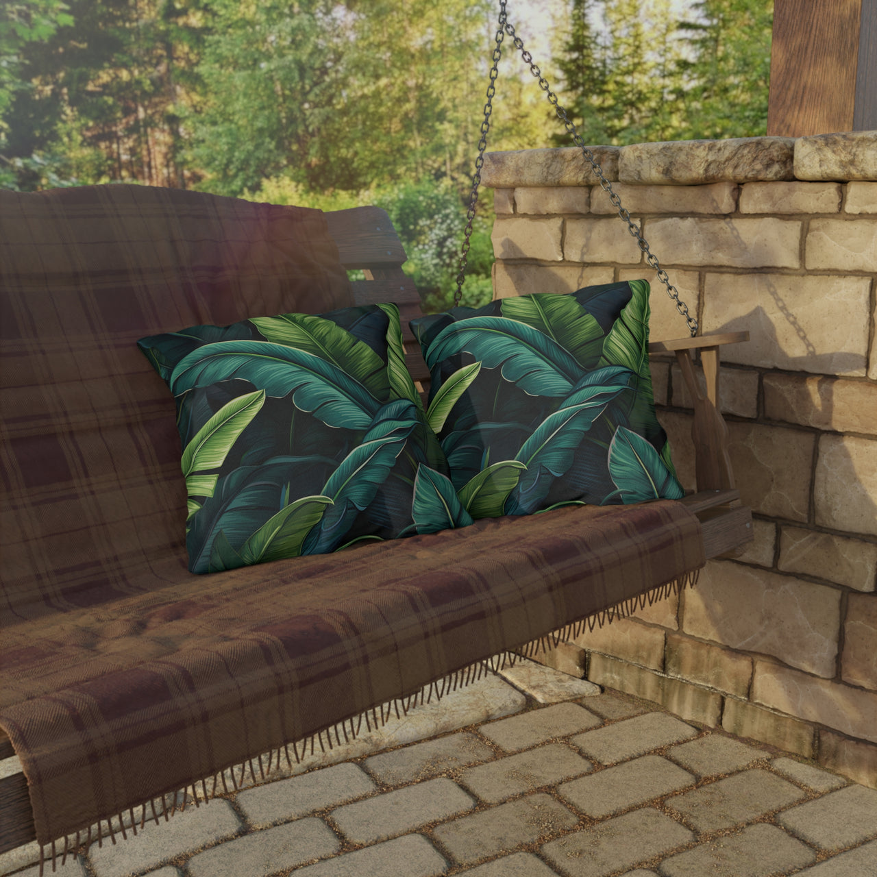 Wooden swing with green leaf-patterned cushions on a stone patio