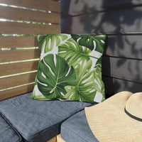Thumbnail for Green leaf-patterned pillow on a gray cushion with a straw hat on a wooden bench.