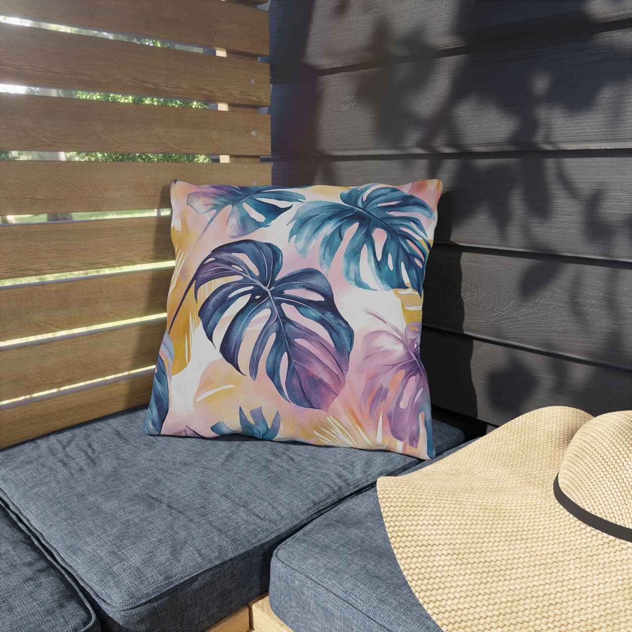 Outdoor seating area with a colorful leaf-patterned pillow and a straw hat.