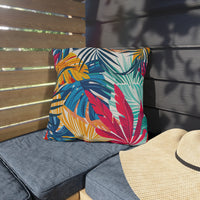 Thumbnail for Colorful leaf-patterned pillow on a gray cushion next to a straw hat against a wooden and gray wall.