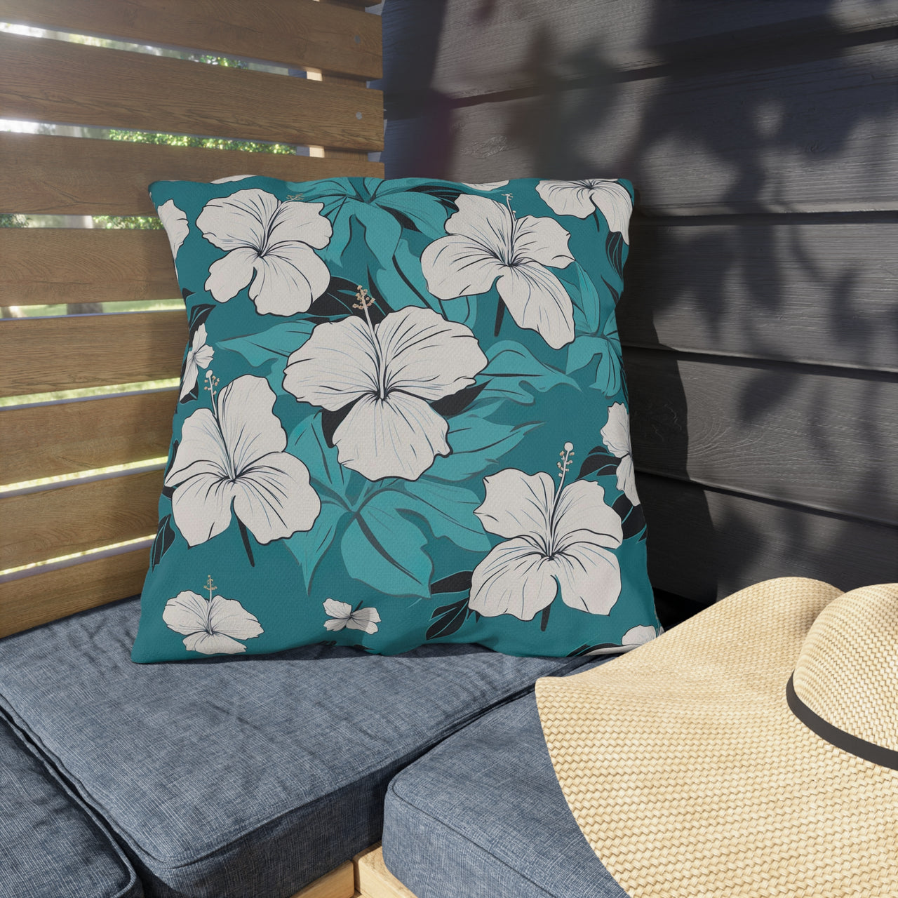 Floral pillow on a bench with a straw hat nearby