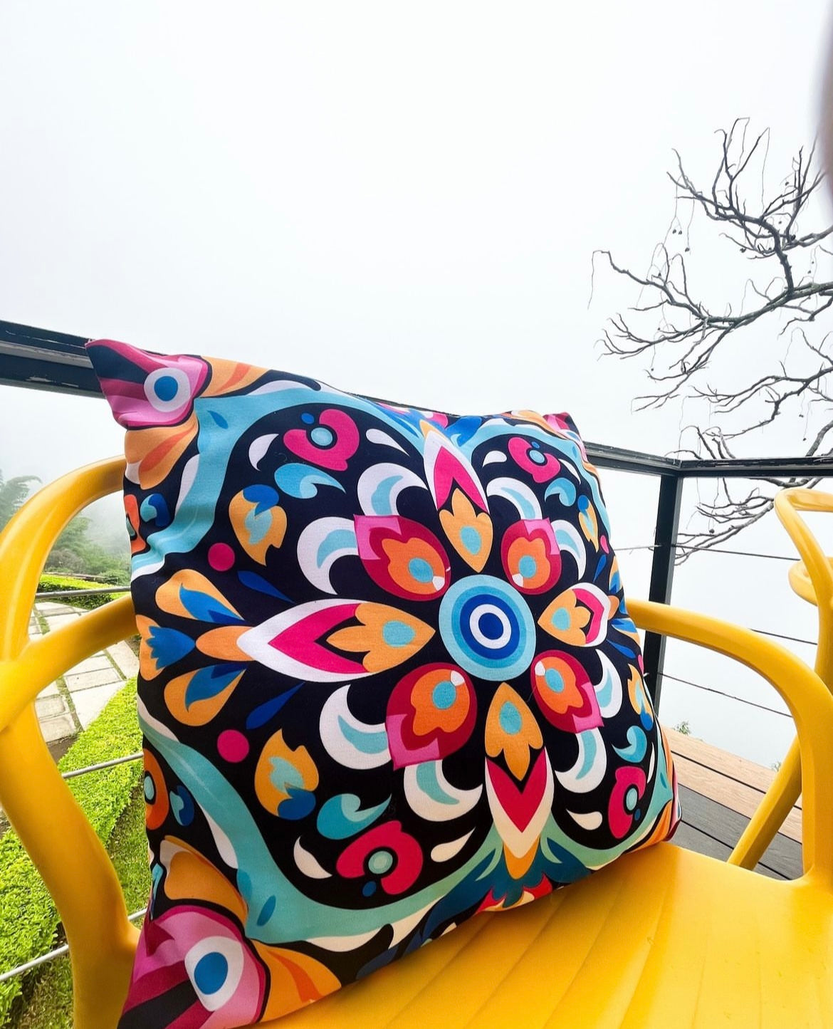 Colorful patterned cushion on a yellow chair outdoors