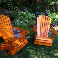 Thumbnail for Two wooden Adirondack chairs in a garden setting with plants and birds.
